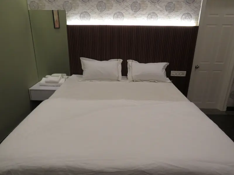 1 BHK bedroom with double bed, fresh white linen and backlit headboard