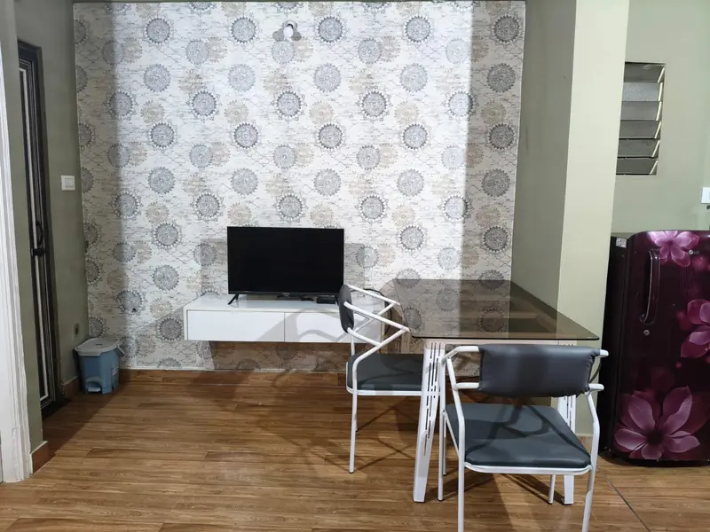 1 BHK living area with TV, dining table and refrigerator